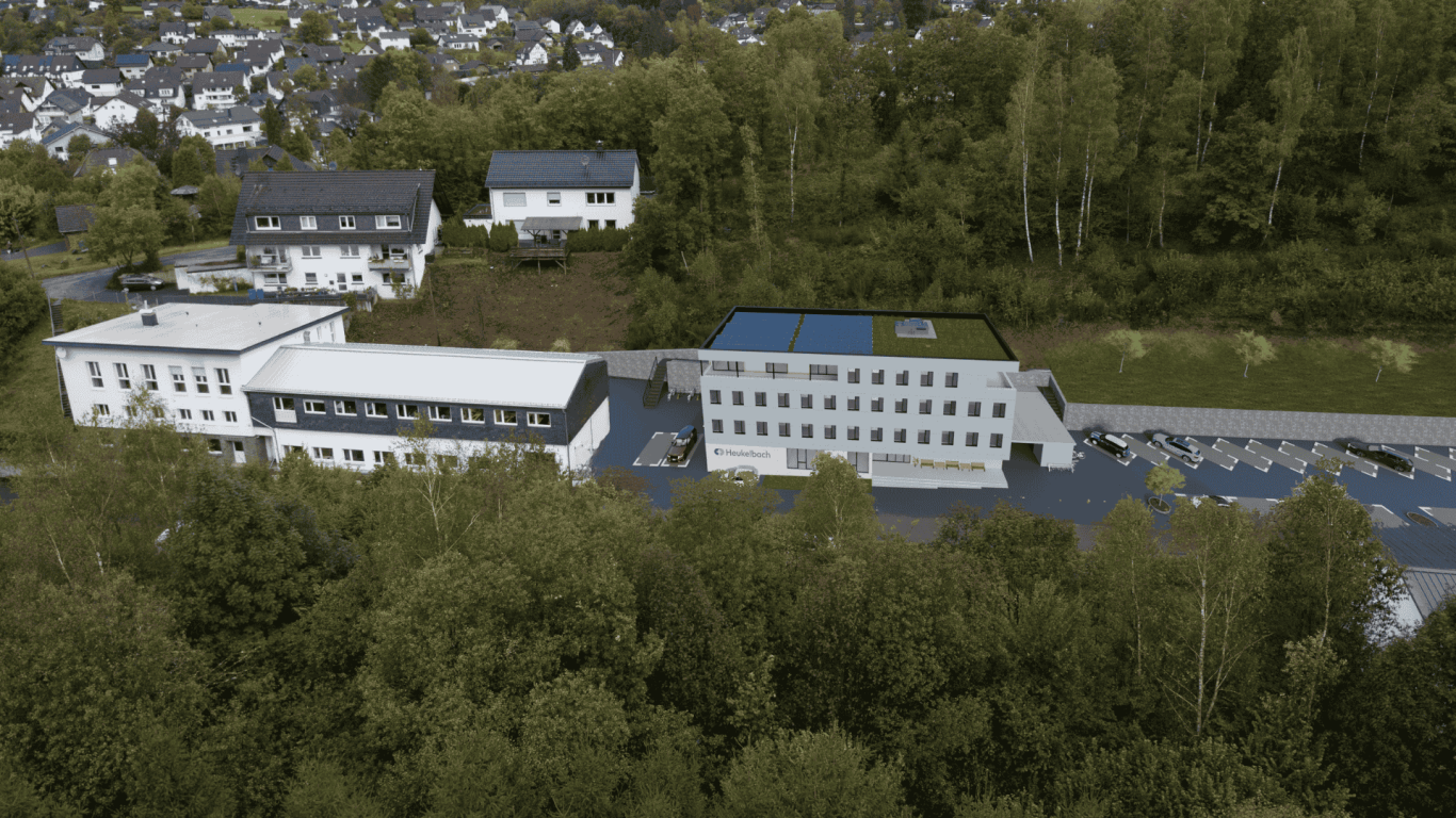 Bürogebäude eingebettet in Drohnenaufnahme - Stiftung Heukelbach Moderne Gebäudeansicht umgeben von Bäumen und Fahrzeugparkplätzen.